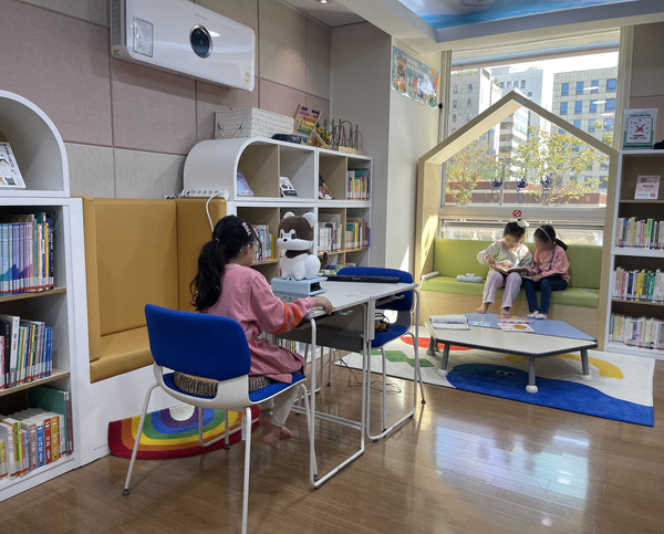 강아지 모양의 로봇 포메와 어린이가 도서관에서 교감하고 있는 모습.